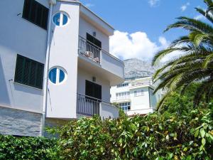 ein weißes Gebäude mit Palmen und Bergen im Hintergrund in der Unterkunft Apartments Cobra - excellent location in Tučepi