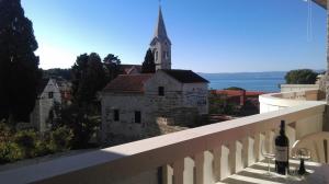 a bottle of wine sitting on a balcony with a church at Apartments and rooms Rest - close to the sea & comfortable in Sumartin