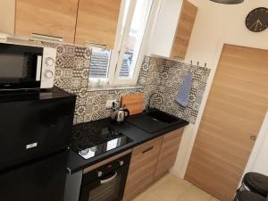 cocina con fogones negros junto a un microondas en Appartement refait par architecte. Proche de la gare et le centre de Reims, en Reims 15 fotos más