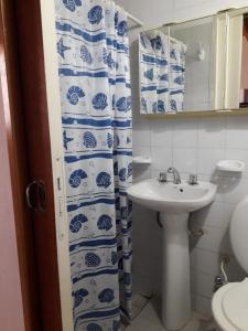 a bathroom with a sink and a blue and white shower curtain at AMANECERES LAS GRUTAS II in Las Grutas