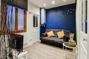 a living room with a couch and a blue wall at LE DORMEUR DU VAL - TOPDESTINATION DIJON - Centre ville - Classé 3 étoiles in Dijon