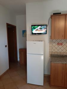 una nevera blanca en una cocina con TV en la pared en Villetta sul mare, en Capo Vaticano