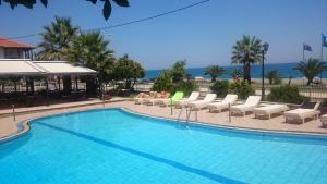 a large swimming pool with lounge chairs and the ocean at Golden Beach Hotel in Agiokampos