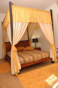 a bedroom with a canopy bed with yellow curtains at Casa Da Canada in Seia