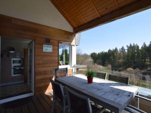 una terrazza in legno con tavolo e sedie in legno di Luxury apartment with sauna over a lake a Robertville