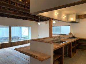 a large kitchen with a large wooden counter top at ゲストハウス さんかくワサビ in Saiki