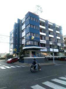 Apartahotel Jardines Metropolitanos في سانتياغو دي لوس كاباليروس: شخص يركب دراجة نارية أسفل شارع أمام مبنى