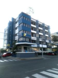 Apartahotel Jardines Metropolitanos في سانتياغو دي لوس كاباليروس: مبنى ازرق كبير فيه سيارات تقف امامه