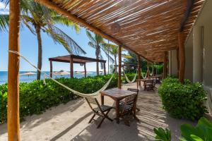 a hammock on the beach with tables and chairs at Mereva Tulum in Tulum