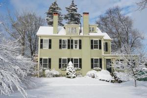 a green house with a chimney in the snow at Delano Homestead Bed and Breakfast in Fairhaven