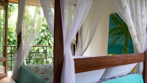 um quarto com uma cama com cortinas e uma janela em Estalagem Camburi em Camburi