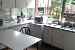 y cocina con mesa y microondas. en Habitación en casa con gran jardín en San Isidro