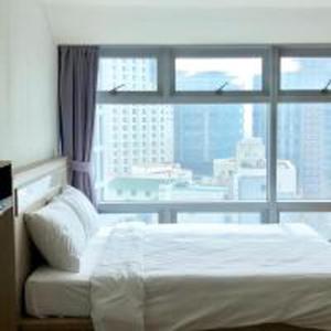 a white bed in a room with a large window at Busan Popcorn Hostel in Busan