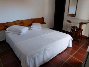 a bed with white sheets and pillows in a room at Pousada Nayane in Barequeçaba