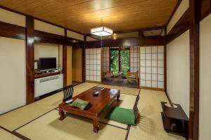 a living room with a wooden table and a television at Furusato in Takayama