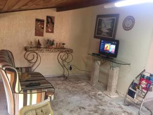 Una sala de estar con un sofá y un televisor. en Sótão Studio Relax, en Peruíbe