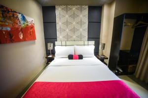 um quarto com uma grande cama branca e um cobertor vermelho em Eloisa Royal Suites em Mactan