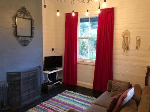 a living room with red curtains and a couch at Piccolo in Leura