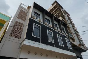 un edificio en blanco y negro con ventanas blancas en RedDoorz Syariah near RSUD Siti Fatimah Palembang, en Palembang