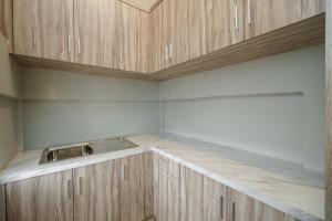 cocina con armarios de madera y encimera en RedDoorz Syariah near RSUD Siti Fatimah Palembang, en Palembang