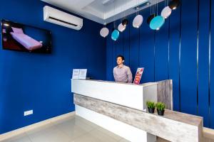 a man standing at a counter in a blue room at Jenjarom Boutique Hotel in Banting