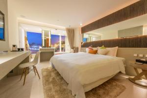 um quarto com uma grande cama branca e uma secretária. em Inhouse Hotel Yehliu em Wanli