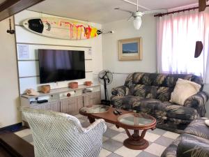 a living room with a couch and a flat screen tv at Quatro Ilhas Beach Hostel in Bombinhas