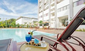 a table with a drink and a plate of food next to a pool at Raia Hotel & Convention Centre Terengganu in Kuala Terengganu