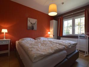 een slaapkamer met een groot bed met oranje muren bij Holiday home in the middle of nature with sauna in Longfaye
