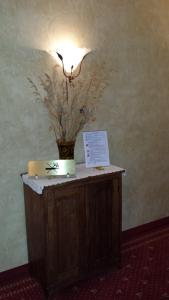una mesa con una lámpara y un jarrón de flores. en Hotel Pesek, en San Dorligo della Valle