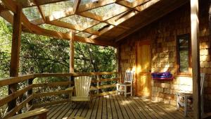 un porche de una cabaña de madera con 2 sillas en River Lodge en Pucón