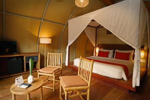 1 dormitorio con cama con dosel, sillas y mesa en Templation Hotel en Siem Riep