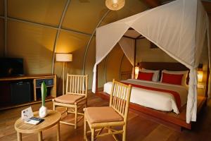 a bedroom with a canopy bed with chairs and a table at Templation Hotel in Siem Reap +76 photos