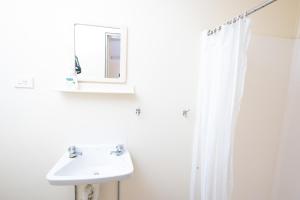 a white bathroom with a sink and a mirror at Rockhampton Backpackers YHA in Rockhampton