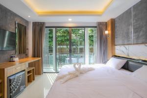 a bedroom with a large white bed and a television at The Mantra Hotel Kata Noi in Kata Beach