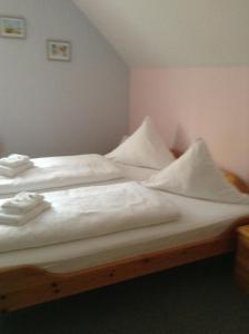 Schlafzimmer mit einem Bett mit weißer Bettwäsche und Kissen in der Unterkunft Hotel Mühleneck in Hage
