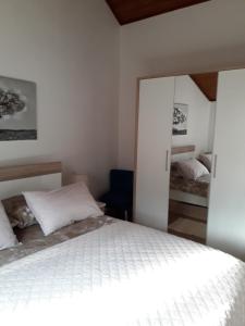 Un dormitorio con una cama blanca y un espejo. en Ana Apartment, en Šibenik
