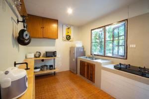 a kitchen with a sink and a refrigerator and a window at Surin House in Surin Beach