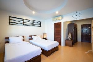 a bedroom with two beds and a clock on the wall at Surin House in Surin Beach