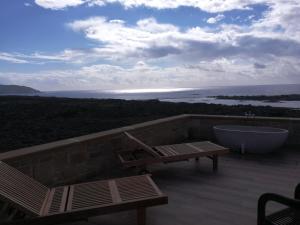 a bath tub and a bench on a deck with the ocean at Elafonisi Villa above the Beach in Elafonisi
