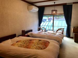 a row of four beds in a room with a window at Tsukinoya in Hakone