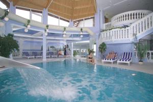 a swimming pool with a waterfall in a building at Landgasthof & Hotel Waldow in Guben
