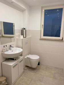 a white bathroom with a toilet and a sink at Szenetreff City in Würzburg