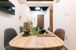 a wooden table with chairs and a vase on it at TORA HOTEL Tokyo-Rikugienn 寅ホテル 六義園 A in Tokyo