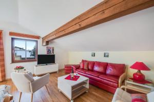 ein Wohnzimmer mit einem roten Sofa und einem TV in der Unterkunft Alpenblick in Eggstätt