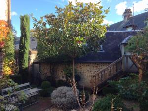 a garden with a bench and a tree at La Cour Sainte Catherine demeure de charme in Honfleur