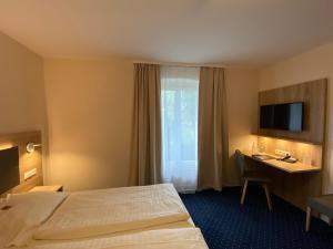 a hotel room with a bed and a desk and a television at Römerhof in Stuttgart