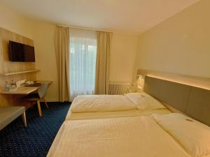 シュトゥットガルトにあるルーマーホフのベッド2台とデスクが備わるホテルルームです。