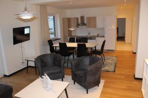a living room with a table and chairs and a kitchen at Dünenhaus Wohnung 7 in Lübeck