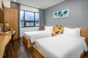 um quarto de hotel com duas camas e uma secretária em Magnolia Hotel em Da Nang